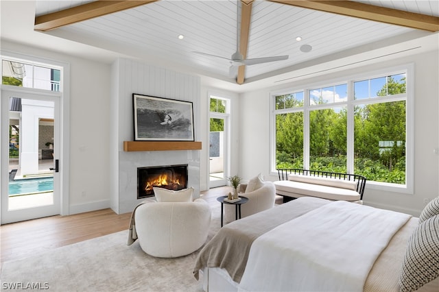 bedroom with access to exterior, ceiling fan, wood-type flooring, multiple windows, and a fireplace