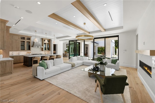 living room with a tray ceiling, light hardwood / wood-style flooring, wood ceiling, and a premium fireplace