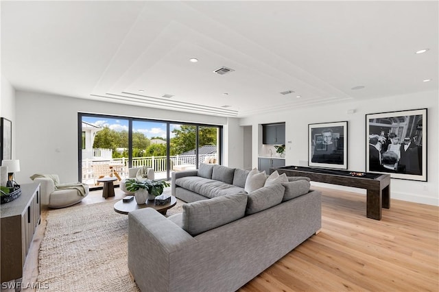 living room with light hardwood / wood-style floors and a tray ceiling