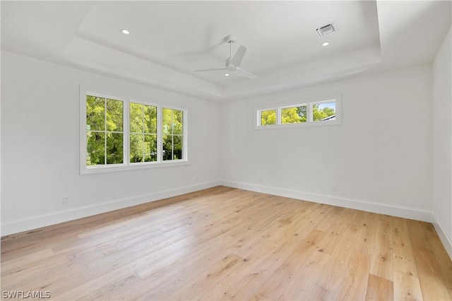 spare room featuring light hardwood / wood-style floors, a raised ceiling, and ceiling fan