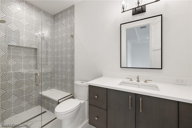 bathroom featuring a tile shower, vanity, and toilet