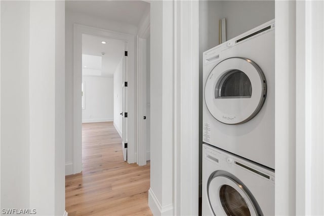 clothes washing area with stacked washer and dryer and light hardwood / wood-style flooring