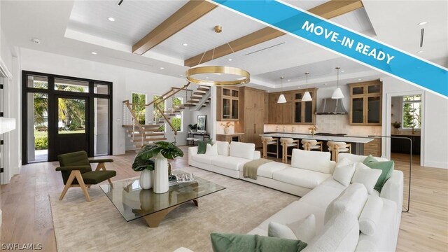 living room with beam ceiling, a tray ceiling, and light hardwood / wood-style floors