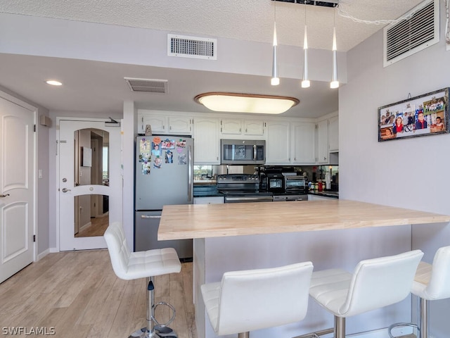 kitchen with a breakfast bar area, kitchen peninsula, stainless steel appliances, and light hardwood / wood-style floors