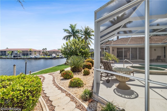 view of patio / terrace featuring glass enclosure and a water view