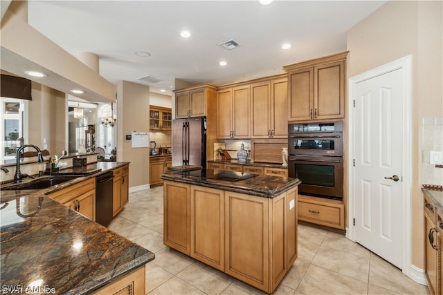 kitchen featuring sink, light tile floors, dark stone countertops, black appliances, and a center island