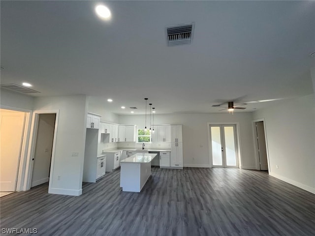 kitchen with a kitchen island, ceiling fan, white cabinets, hanging light fixtures, and sink