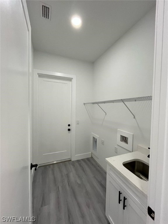 clothes washing area with cabinets, sink, light wood-type flooring, electric dryer hookup, and hookup for a washing machine