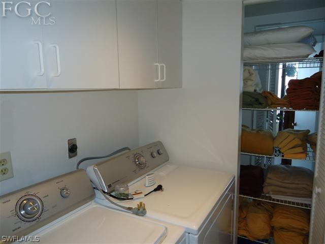 clothes washing area with cabinets and washing machine and dryer