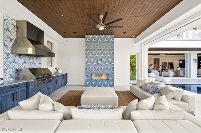 living room featuring a tiled fireplace, ceiling fan, sink, and wood ceiling