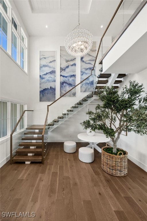 staircase featuring a chandelier, hardwood / wood-style floors, and a towering ceiling