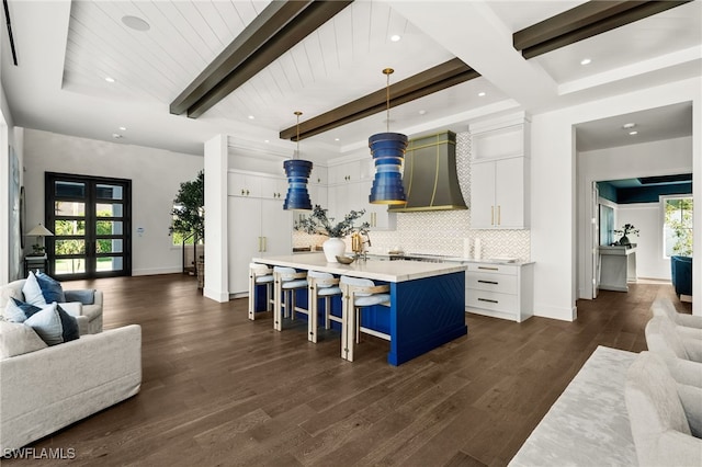 interior space featuring pendant lighting, dark hardwood / wood-style flooring, white cabinetry, and an island with sink