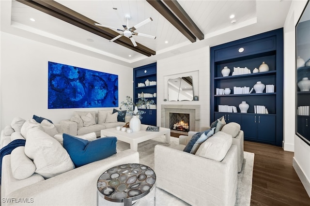 living room featuring built in shelves, ceiling fan, beamed ceiling, a fireplace, and dark hardwood / wood-style floors