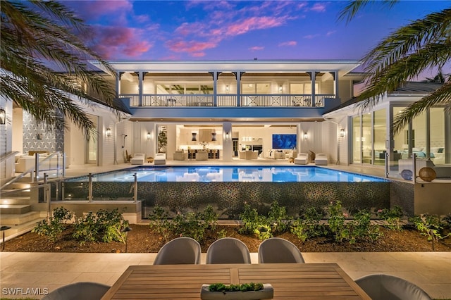 pool at dusk featuring an outdoor living space and a patio area