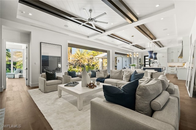 living room featuring beamed ceiling, ceiling fan with notable chandelier, and light hardwood / wood-style floors