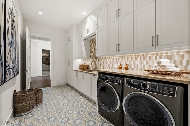 laundry room with cabinets, washing machine and dryer, and sink