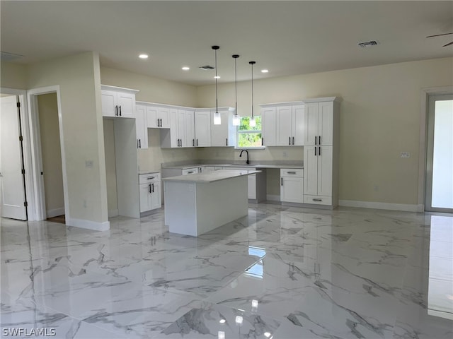 kitchen featuring white cabinets, a center island, sink, and light tile floors