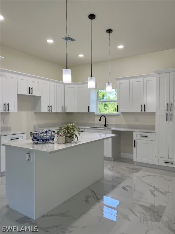 kitchen featuring light tile flooring, a kitchen island, white cabinets, sink, and pendant lighting