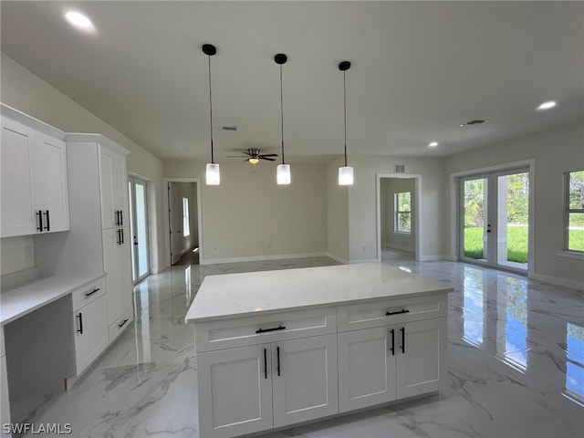 kitchen with light stone countertops, ceiling fan, light tile flooring, hanging light fixtures, and white cabinetry