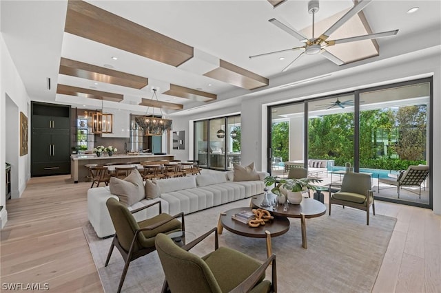 living room featuring ceiling fan with notable chandelier and light hardwood / wood-style flooring