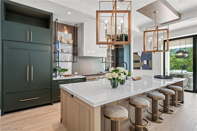 kitchen with paneled built in fridge, a center island with sink, and light wood-type flooring