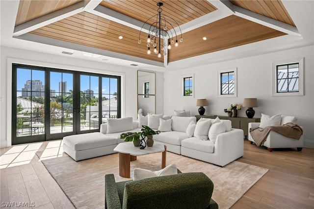 living room with light wood-type flooring, a tray ceiling, an inviting chandelier, and wooden ceiling