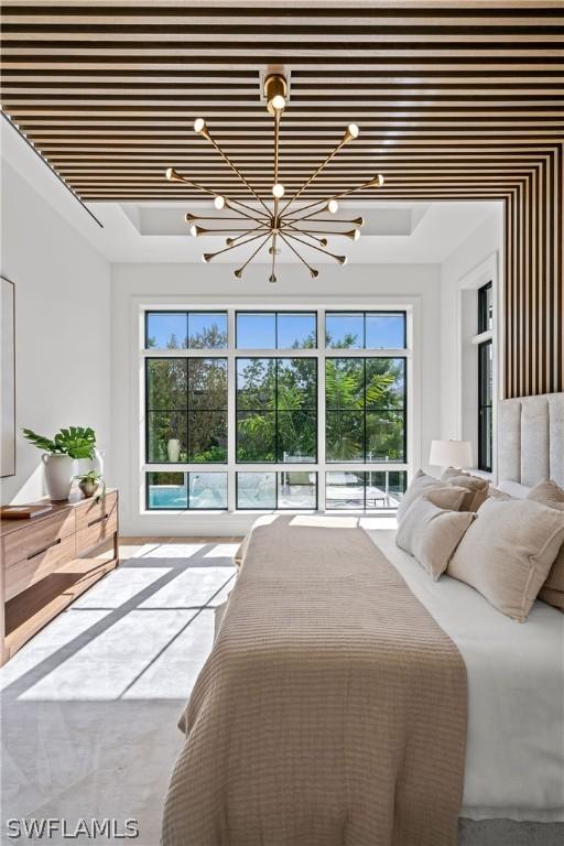 bedroom with a tray ceiling, multiple windows, and an inviting chandelier