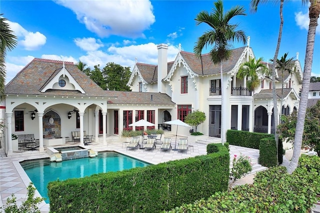 rear view of property featuring a swimming pool with hot tub and a patio