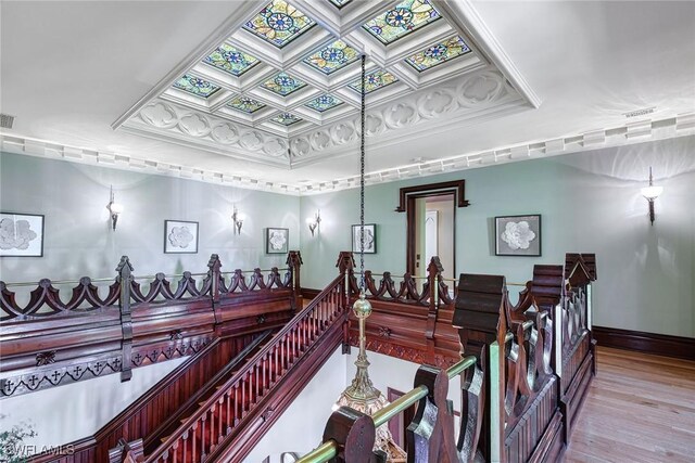 interior space featuring crown molding, coffered ceiling, and light wood-type flooring