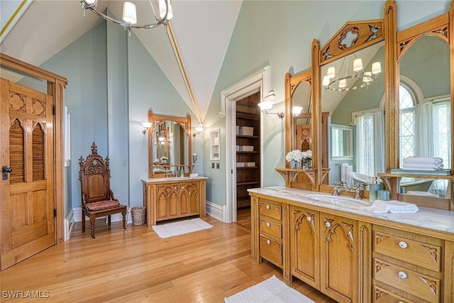 bathroom featuring hardwood / wood-style flooring, vanity, high vaulted ceiling, and a notable chandelier