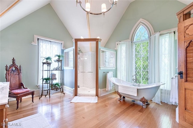 bathroom with hardwood / wood-style flooring, high vaulted ceiling, shower with separate bathtub, and a chandelier