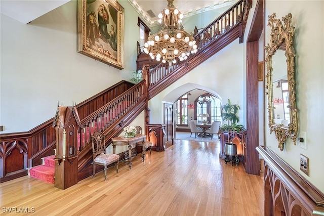 foyer with a high ceiling, light wood-type flooring, and an inviting chandelier