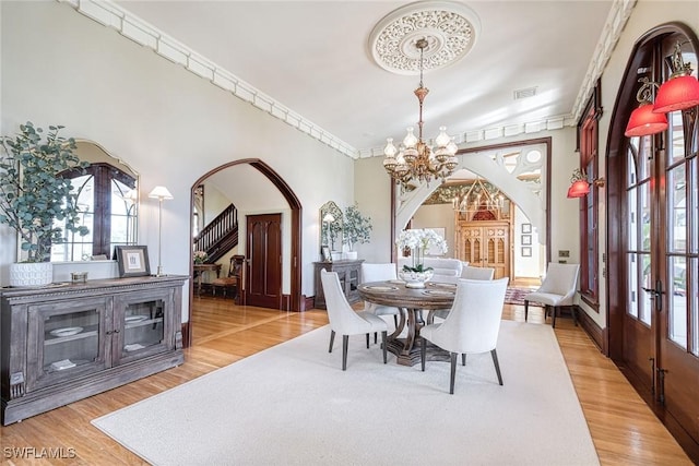 dining area featuring crown molding, a notable chandelier, hardwood / wood-style flooring, and french doors