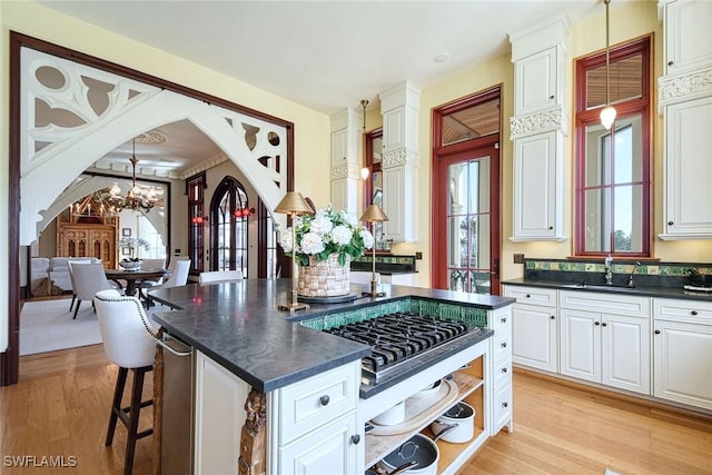 kitchen featuring a kitchen island, sink, white cabinets, and decorative light fixtures