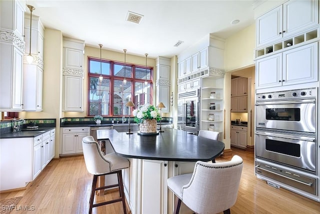 kitchen featuring a breakfast bar, double oven, hanging light fixtures, and white cabinets