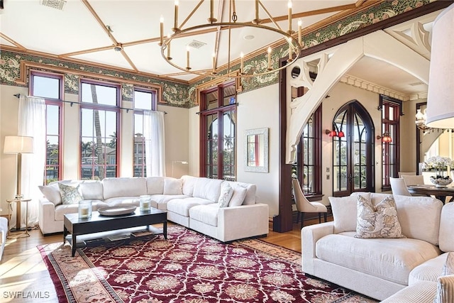 living room featuring ornamental molding, coffered ceiling, wood-type flooring, and a notable chandelier