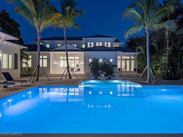 pool at night featuring a patio