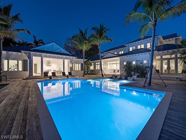 pool at night featuring an outdoor living space and a patio area