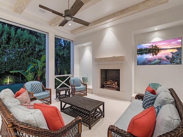 living room with beamed ceiling, ceiling fan, and a fireplace