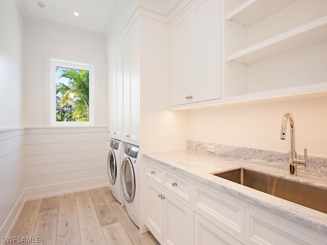 laundry area with cabinets, light wood-type flooring, crown molding, sink, and washer and dryer