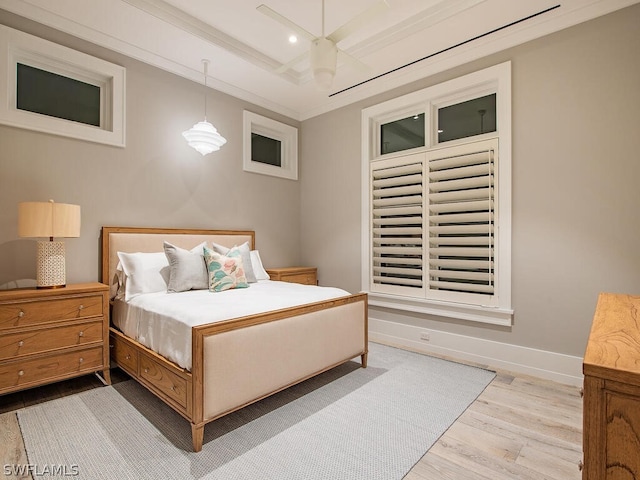 bedroom with light hardwood / wood-style floors, ornamental molding, and a tray ceiling