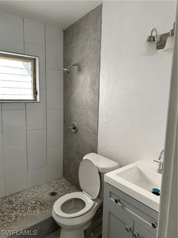 bathroom with vanity, toilet, and tiled shower