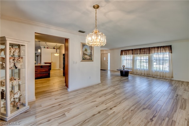 empty room with an inviting chandelier, crown molding, and light hardwood / wood-style floors