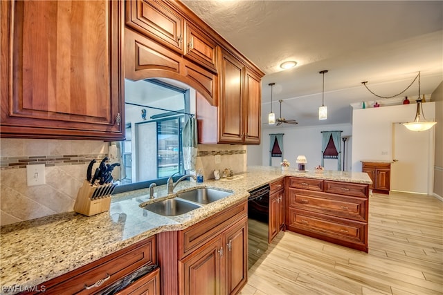 kitchen featuring kitchen peninsula, light stone counters, sink, and pendant lighting