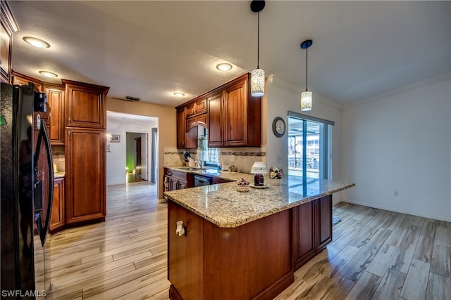 kitchen with backsplash, hanging light fixtures, light hardwood / wood-style flooring, and black fridge