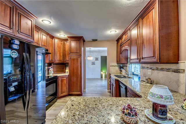 kitchen featuring backsplash, black appliances, light hardwood / wood-style floors, sink, and light stone counters