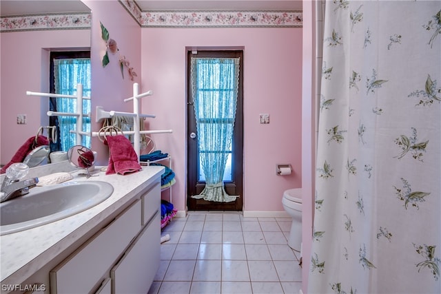 bathroom with plenty of natural light, toilet, large vanity, and tile flooring