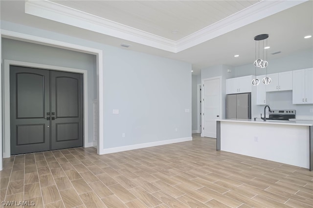 kitchen with pendant lighting, white cabinets, ornamental molding, a tray ceiling, and stainless steel appliances