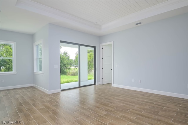 empty room with light wood-type flooring, a raised ceiling, and wooden ceiling