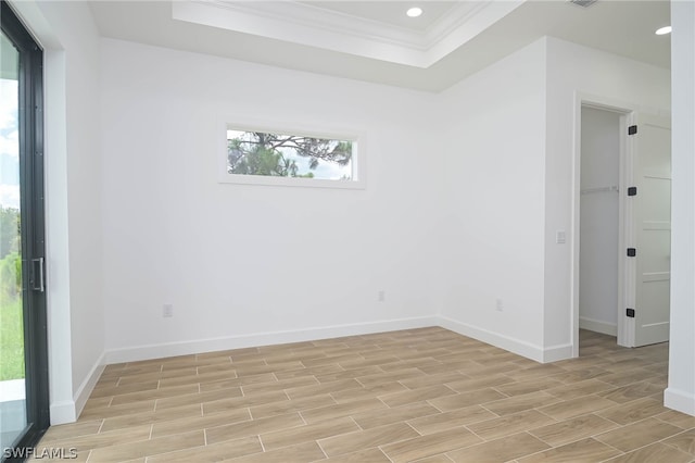 unfurnished room with a raised ceiling and crown molding